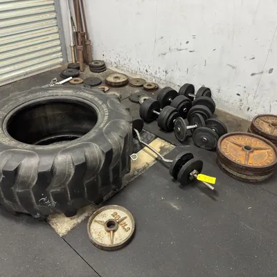 assorted-metal-plate-weights-dumbbells-and-tire-9ac124